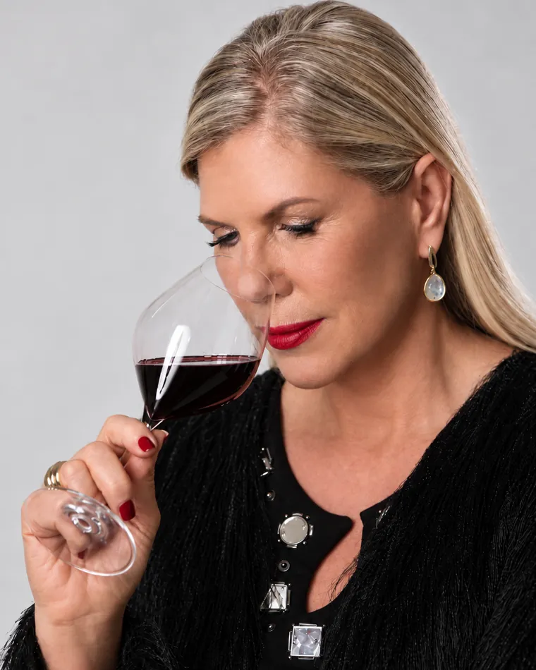 Regina Vanderlinde de olhos fechados, com o nariz na taça de vinho tinto