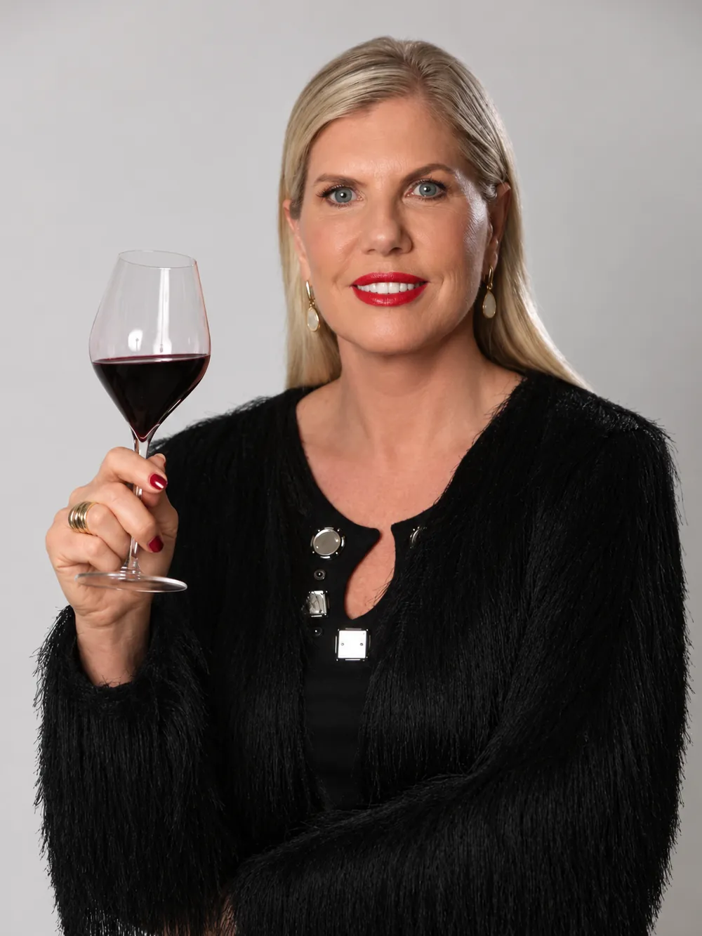 Regina Vanderlinde com uma taça de vinho tinto erguida